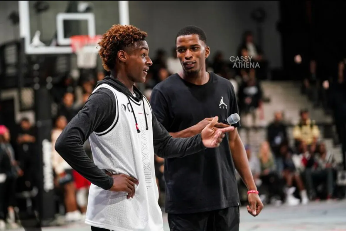 Tyler Bell on the mic in a Jordan shirt, hosting a young player on court in front of a crowd