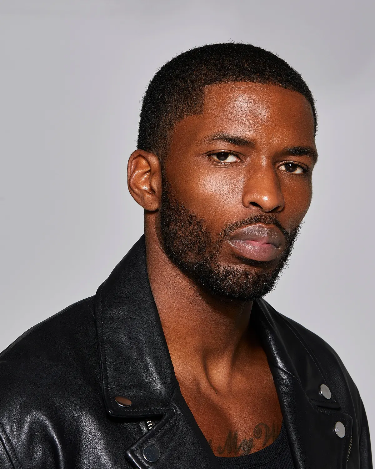 Studio portrait of Tyler Bell in a black leather jacket, serious expression