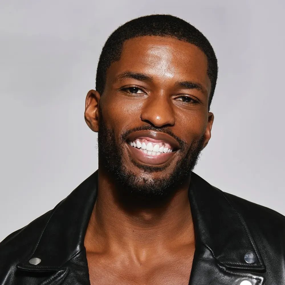 Studio headshot of Tyler Bell laughing in a leather jacket