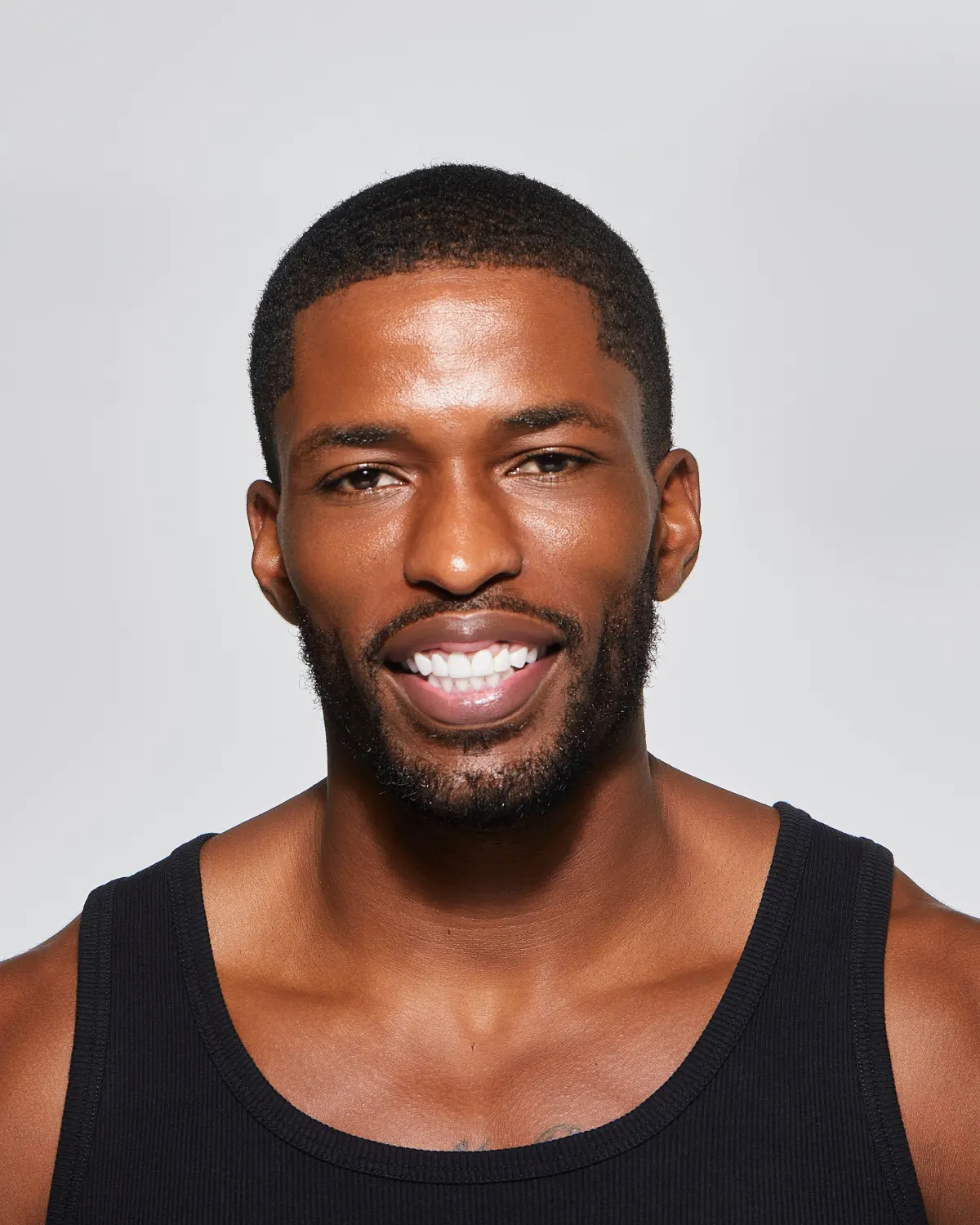 Studio portrait of Tyler Bell smiling in a black ribbed tank top