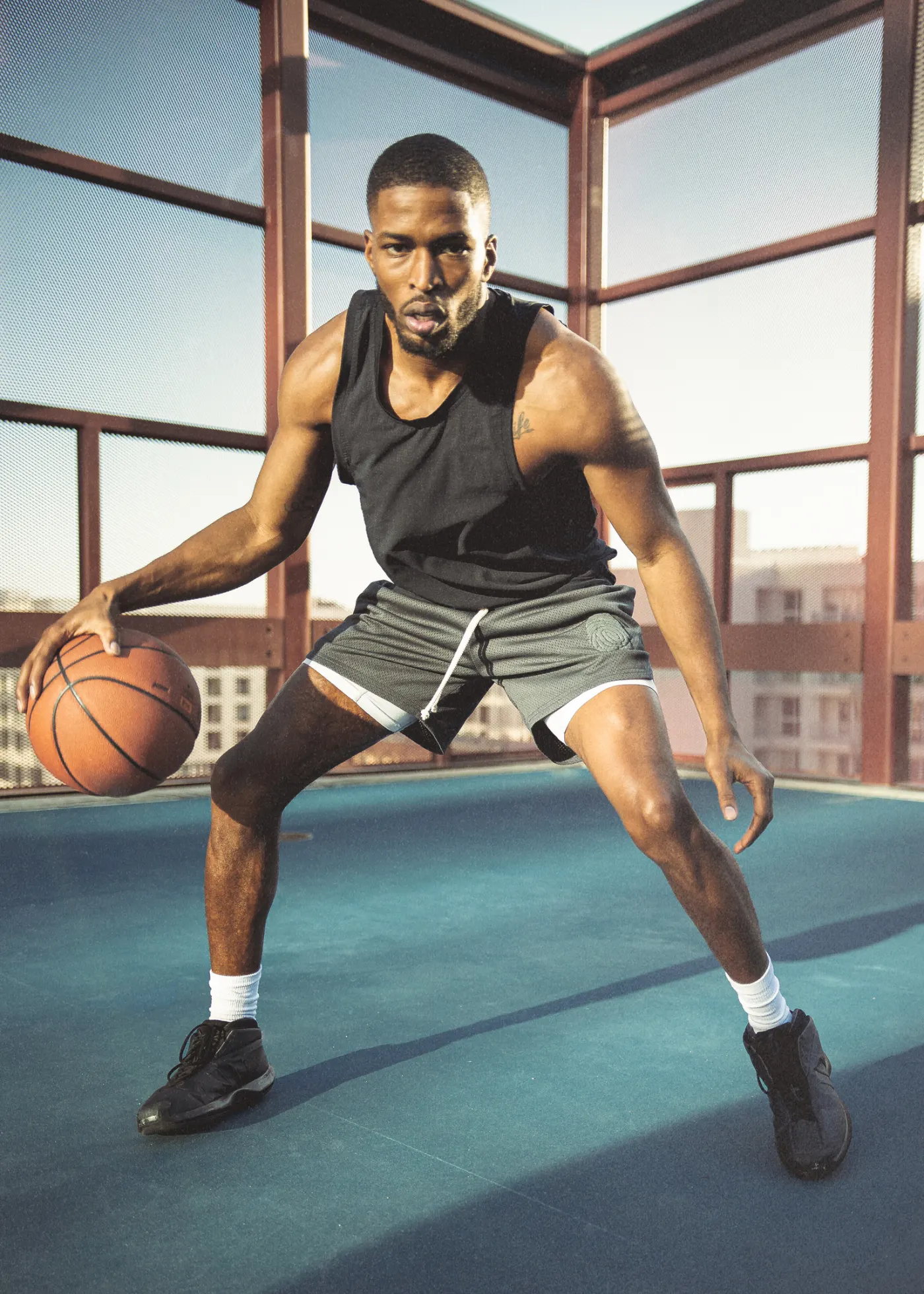 Tyler Bell dribbling on a rooftop court enclosed by rust red steel