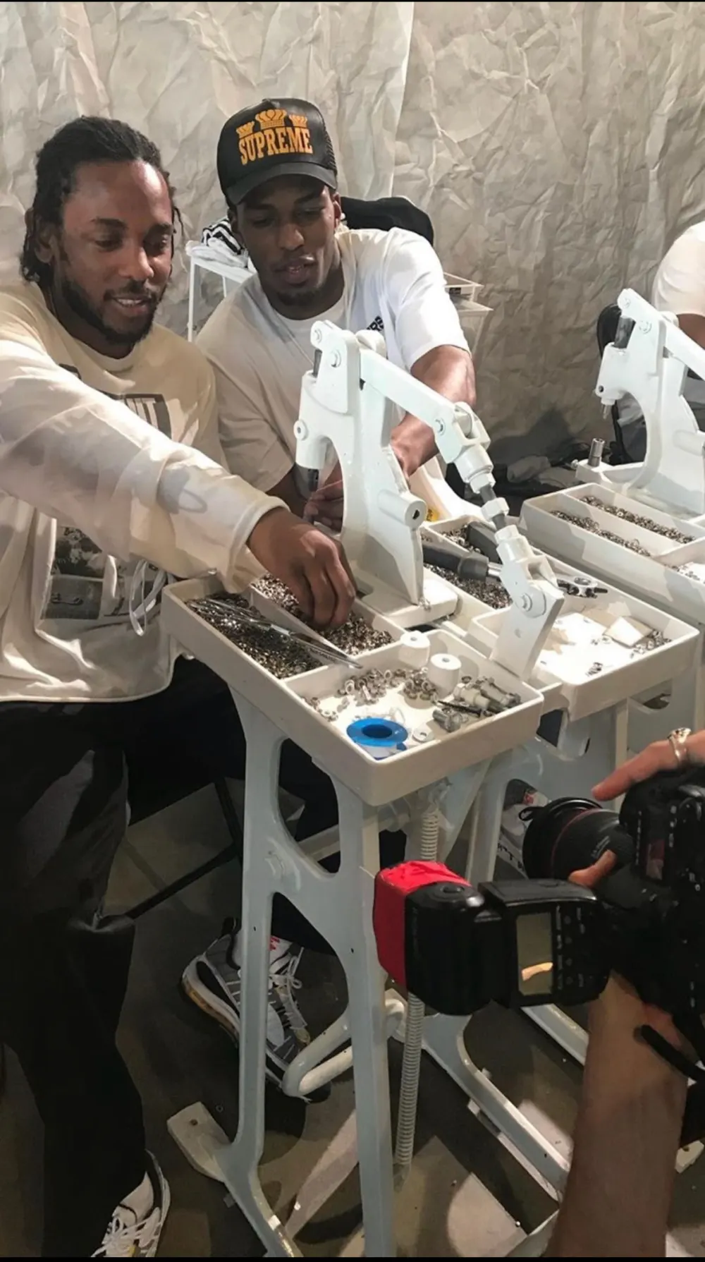 Tyler Bell at a custom build station with an artist, a photographer's camera in the foreground